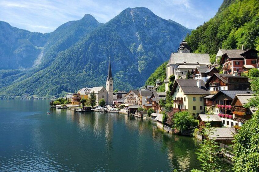 A lakeside village with a church, colorful houses, and mountains in the background. 1
