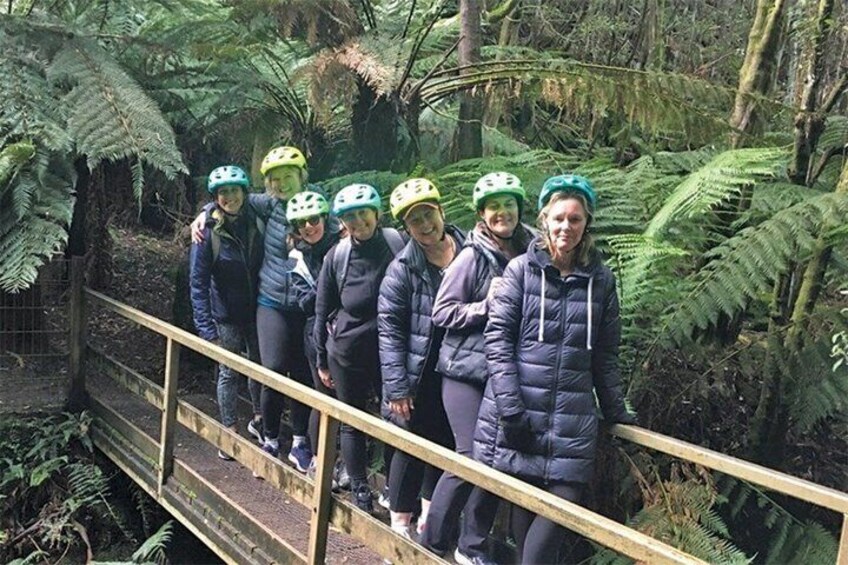 A group of people on a wooden bridge in a forested area. 2