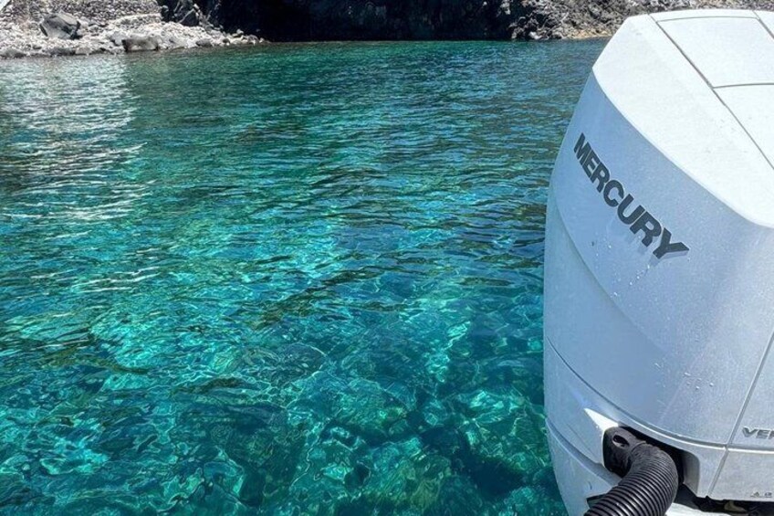 Clear turquoise water, a rocky shoreline, and a Mercury outboard motor. 2