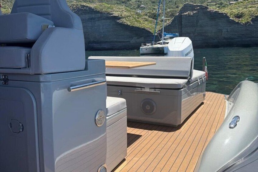A boat's deck with a seating area and a motor. 1