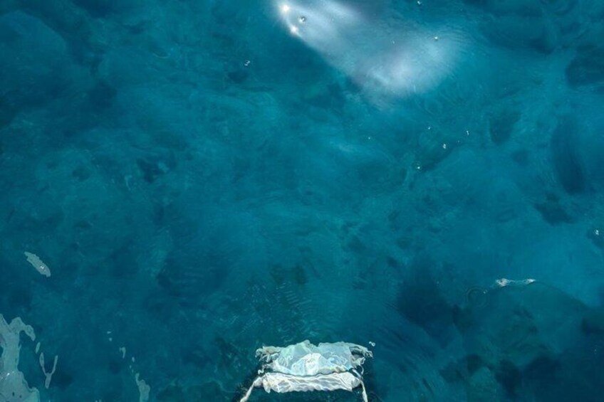 A clear blue underwater scene with a boat and a submerged object. 3