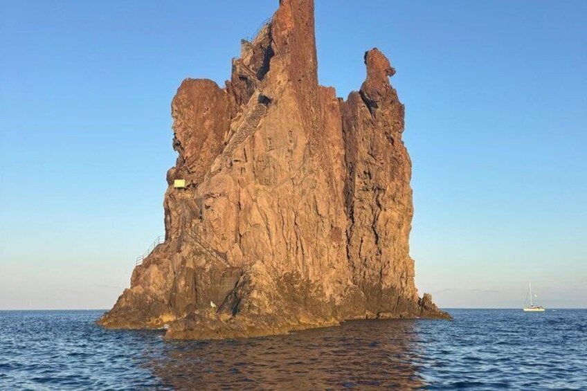 A large rock formation by the sea with a boat in the distance. 5