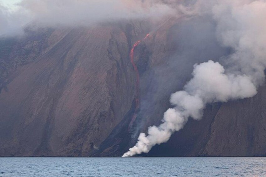 A volcano with smoke and a red lava flow. 4