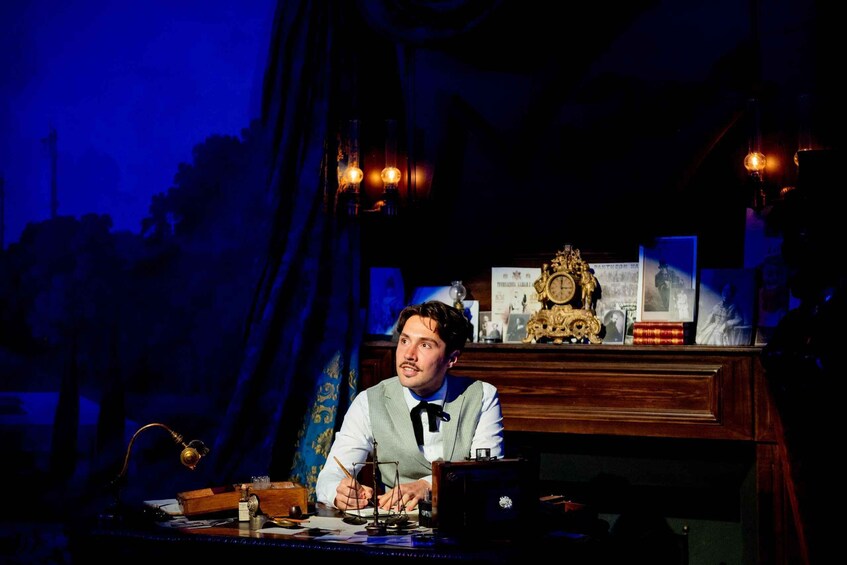 A person at a desk with a vintage typewriter, surrounded by books, a globe, and a clock. 2