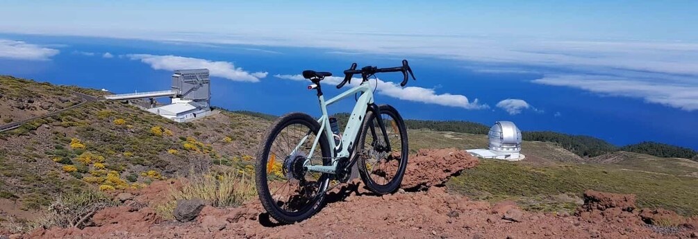 A mountain bike on a rocky terrain with a telescope and a bridge in the background. 3