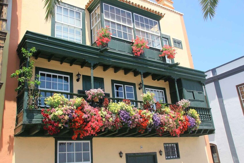 A building with a green balcony adorned with colorful flower boxes. 5