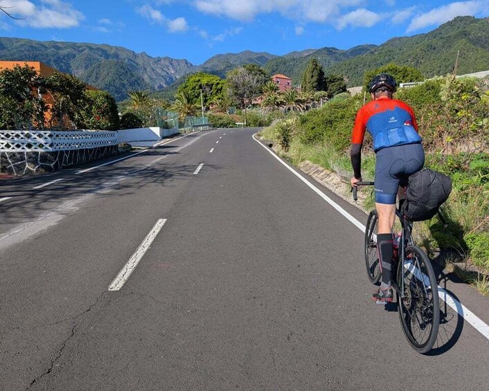 A cyclist on a paved road with a mountain backdrop. 4