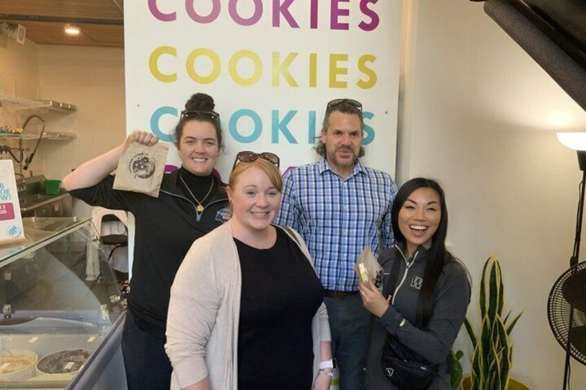 A group of people in a bakery with a sign reading 'COOKIES'. 5
