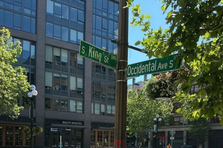 Street signs for S King St and Occidental Ave S, a building with 'Quality Athletics' signage, and a clear blue sky. 4