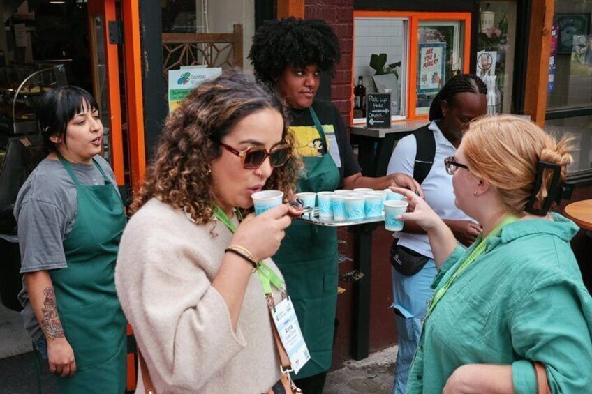 People standing outside a cafe, some holding cups. 3