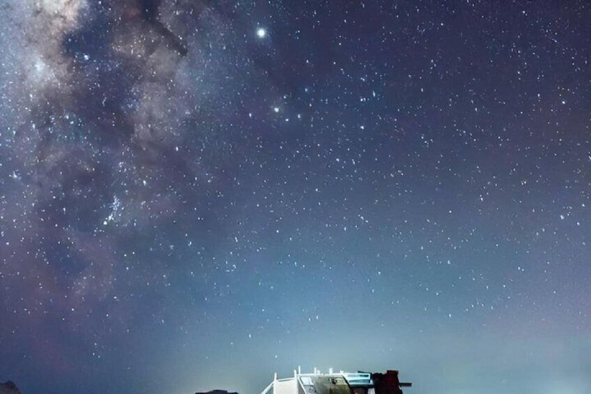 A starry night sky with a visible Milky Way and a bridge structure. 3