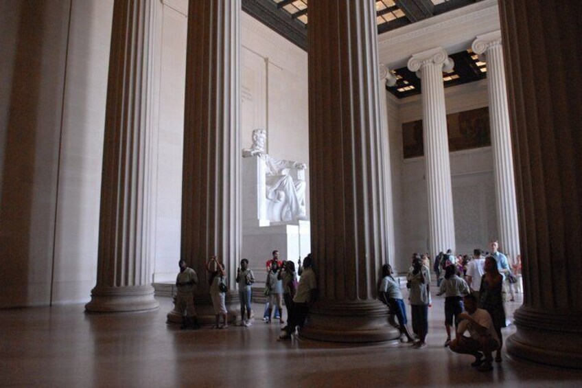A large indoor space with tall columns and a central statue. 5