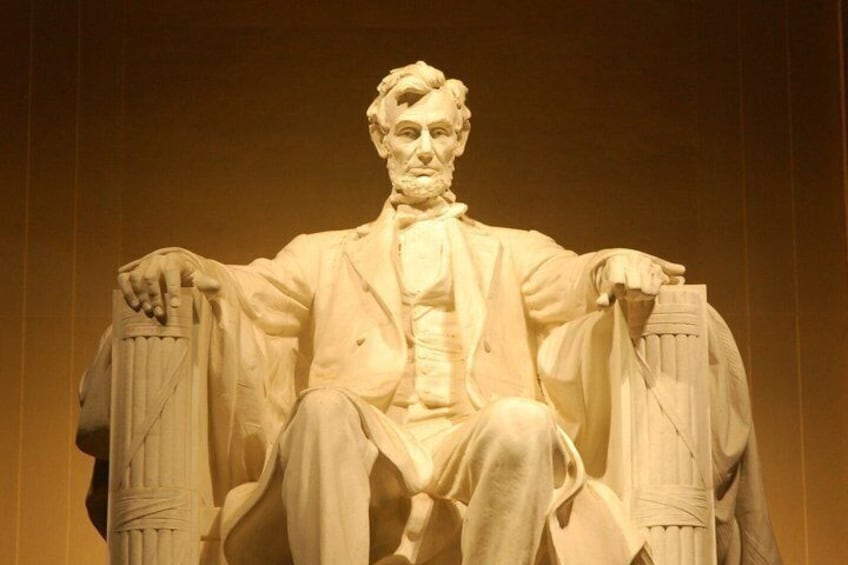 A marble statue of a seated figure with a chair, draped cloth, and a book. 4