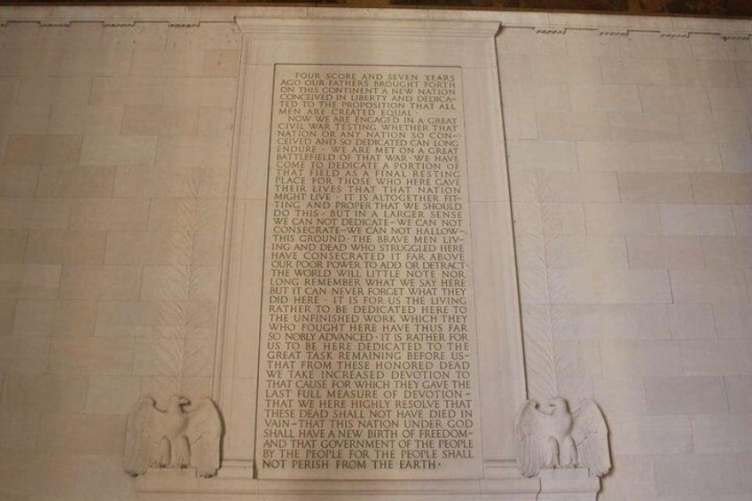 A marble plaque with engraved text and two stone figures at the bottom. 2