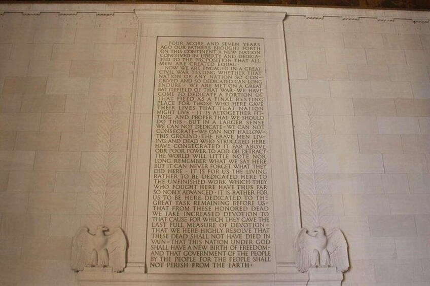 A marble monument with engraved text and two stone figures at the base. 2