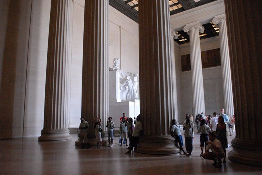 A large indoor space with tall columns, a central sculpture, and people walking around. 3