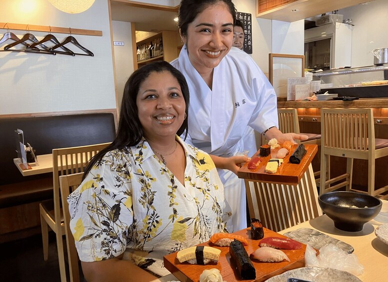 A restaurant interior with wooden furniture, a sushi display, and a person serving food. 3