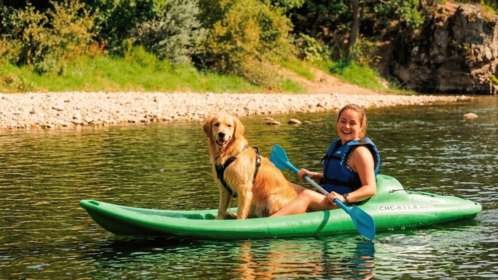 A person kayaking with a dog on a green raft on a river. 2