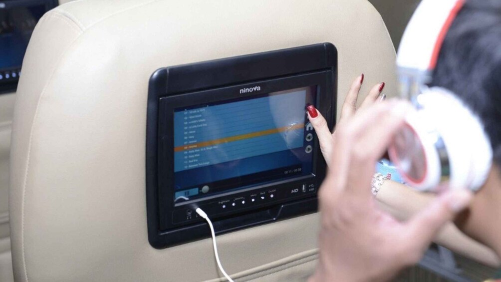 A person using a black in-seat entertainment screen with the brand 'ninova' on an airplane seat. 4