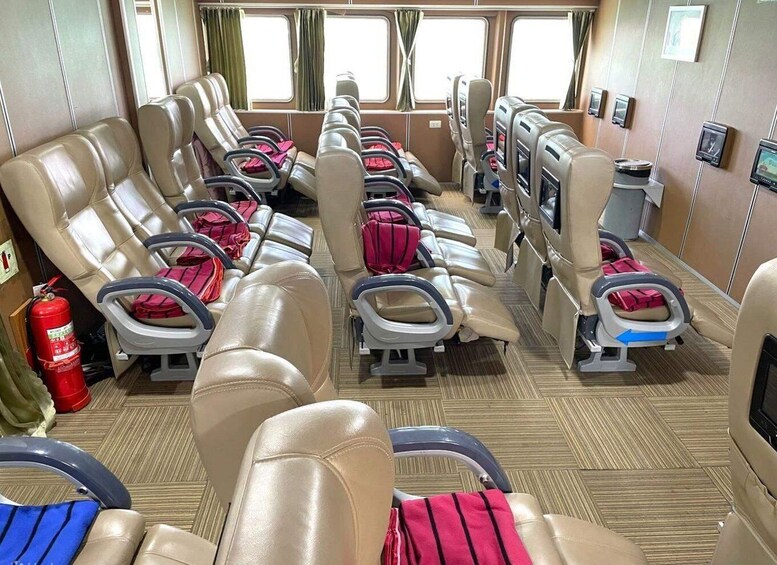 A cruise ship interior with rows of leather seats, some with red blankets, and a fire extinguisher on the left. 2