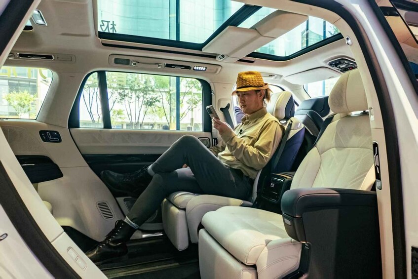 A person seated in a luxury vehicle with a sunroof, leather seats, and a sun visor. 4
