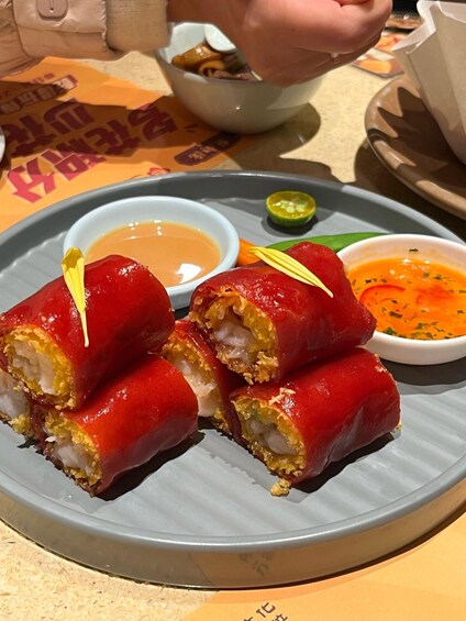 A plate with sushi rolls, a small bowl of sauce, and a green chili. 3