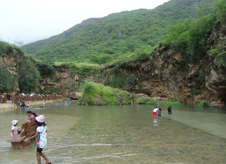 A river with people wading and a bridge in the background. 1