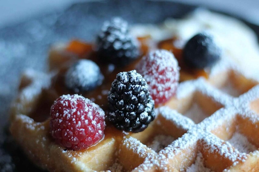 A close-up of a Belgian waffle with powdered sugar and fresh berries. 4
