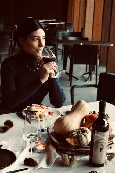 A person seated at a table with a bottle of wine, glasses, and a variety of food items. 5