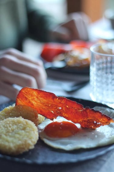 A plate with a slice of orange, a piece of red fruit, and a small round item, possibly a cookie or pastry, on a table. 2