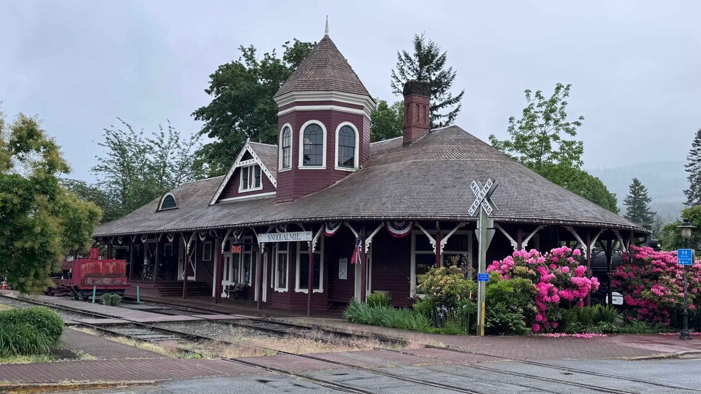 A vintage train station with a distinctive tower and a covered waiting area. 2