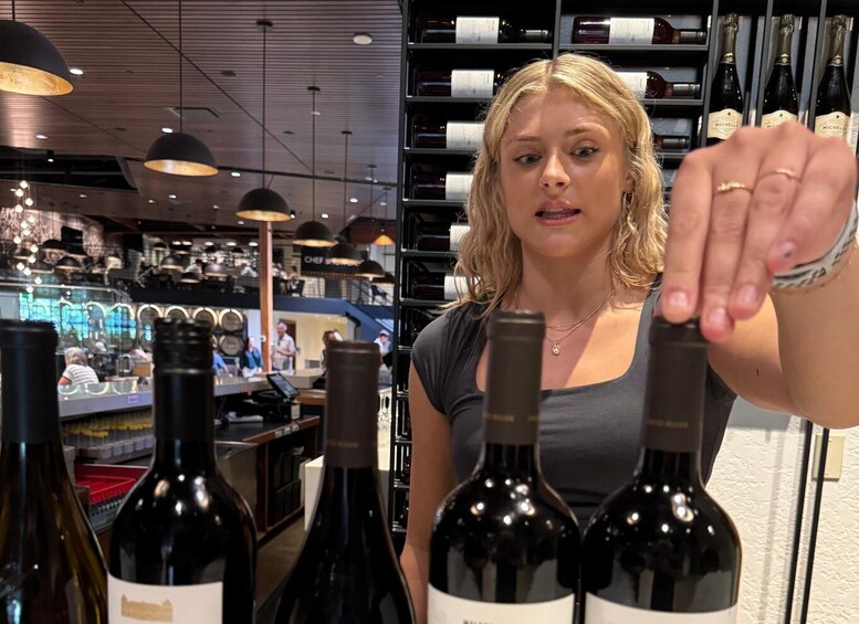 A person holding a wine bottle in a store with shelves of wine bottles in the background. 5