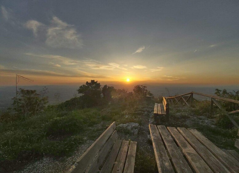 A wooden bench overlooking a sunset view with a clear sky. 2