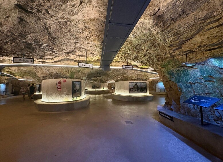 An underground museum with stone walls, circular display platforms, and informational signs. 5