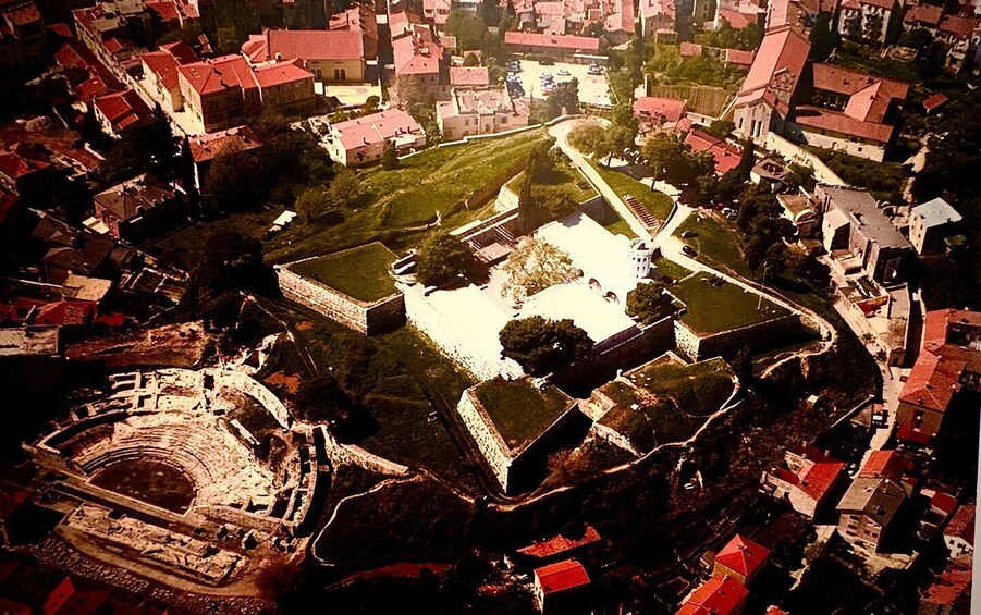 An aerial view of a historic town with a central square, surrounding buildings, and a prominent fortress. 2