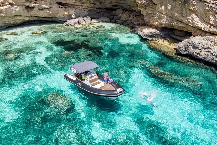 A boat with passengers on a clear turquoise sea surrounded by rocky cliffs. 2