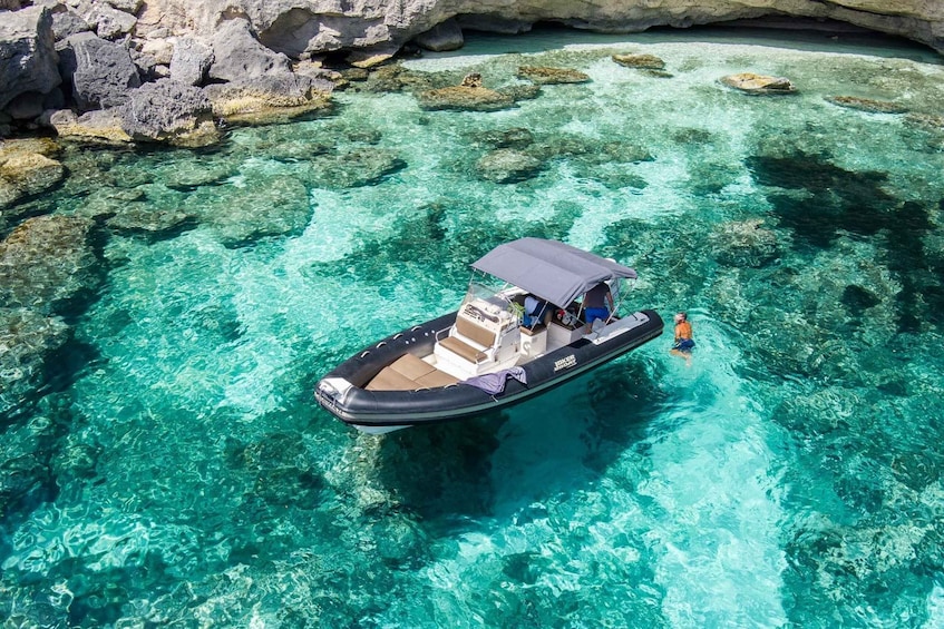 A boat on clear turquoise water near rocky formations. 3