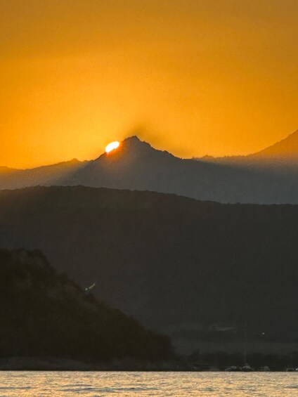 A sunset over a mountain range with a body of water in the foreground. 5