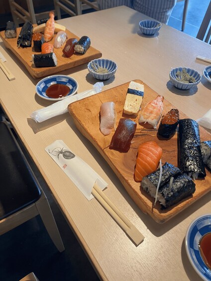 A wooden table with various sushi dishes and small bowls of soy sauce. 3