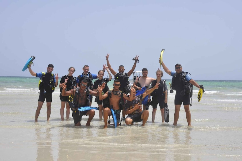 A group of people on a beach with surfboards and snorkeling gear. 1