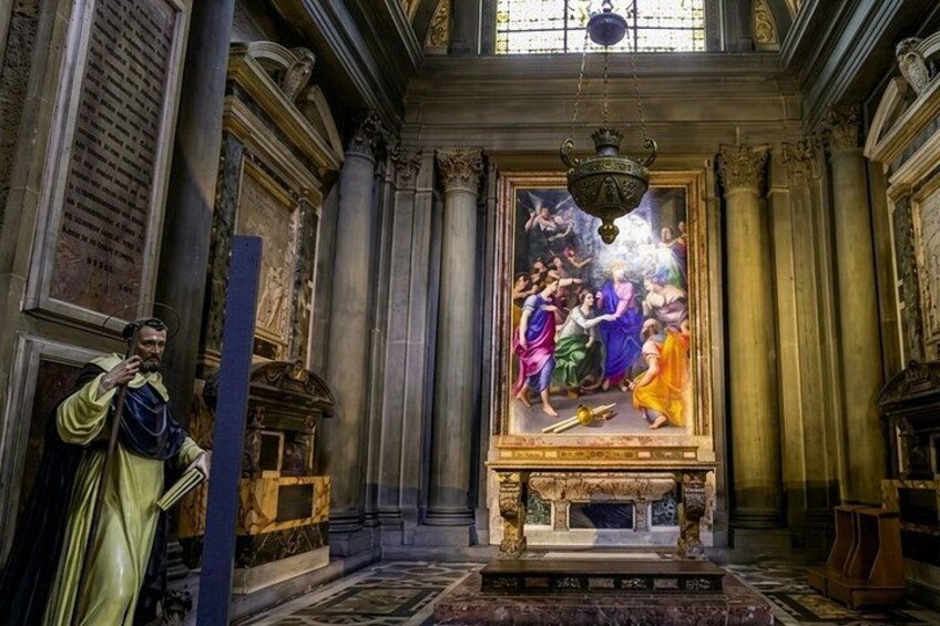 An ornate church interior with a large stained glass window depicting a biblical scene, a statue of a saint, and intricate architectural details. 2