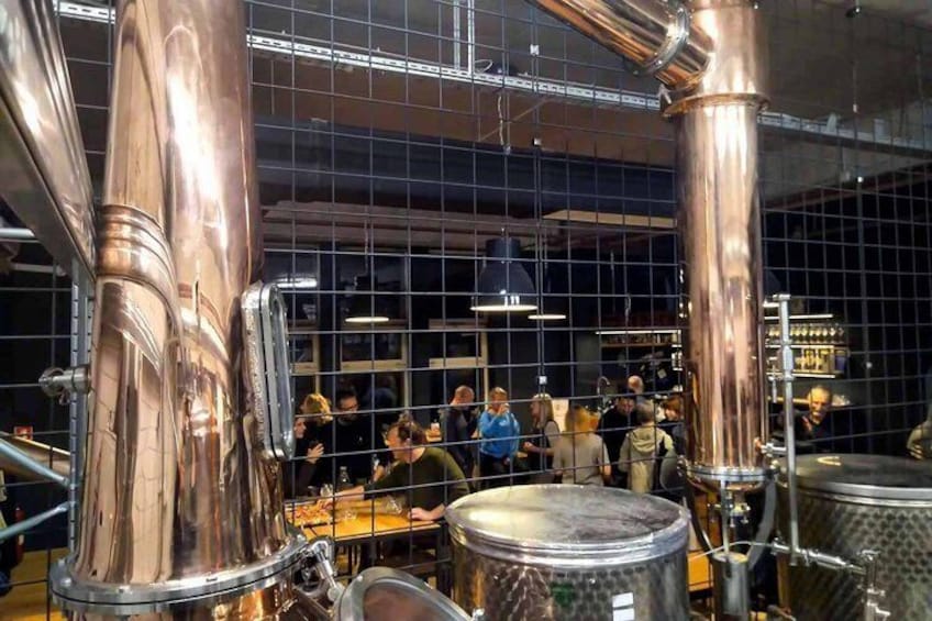 A brewery with copper brewing equipment and a crowd of people. 1