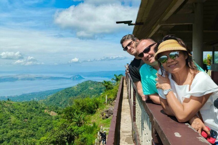 A person leaning on a balcony railing overlooking a mountainous landscape. 5