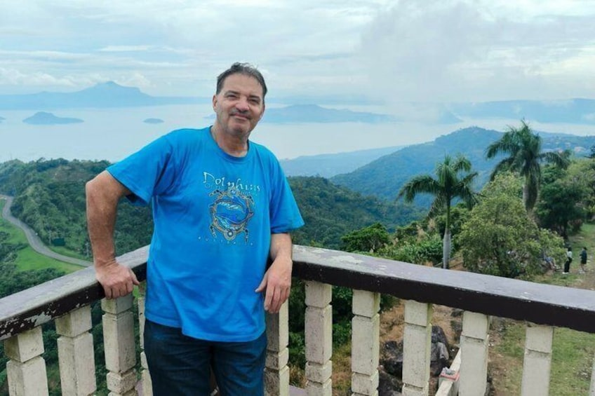 A person standing on a balcony overlooking a mountainous landscape with palm trees. 2