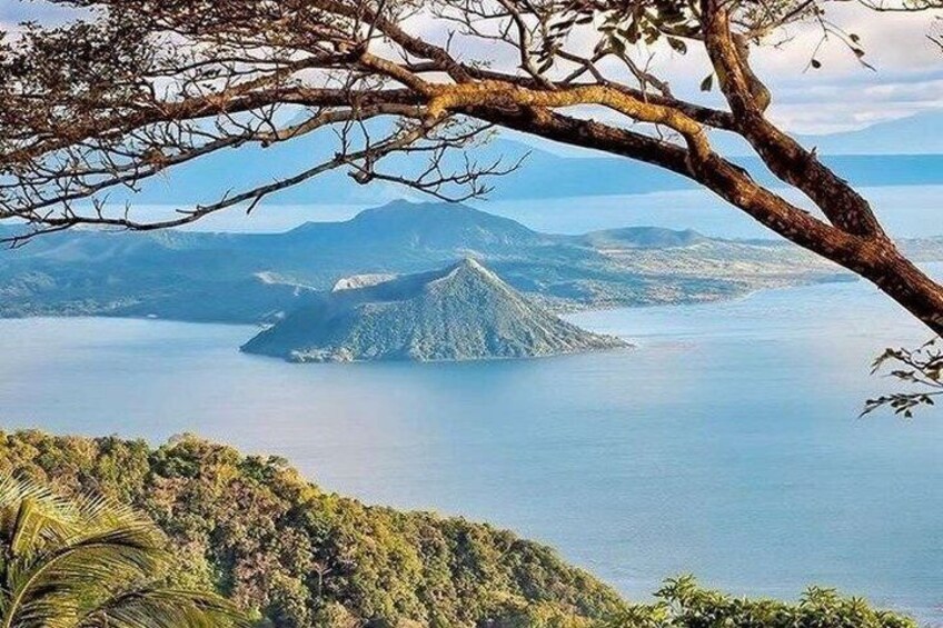 A mountainous landscape with a lake and a tree branch in the foreground. 1