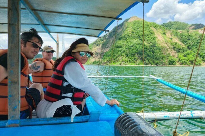 People on a boat with a forested hillside in the background. 4