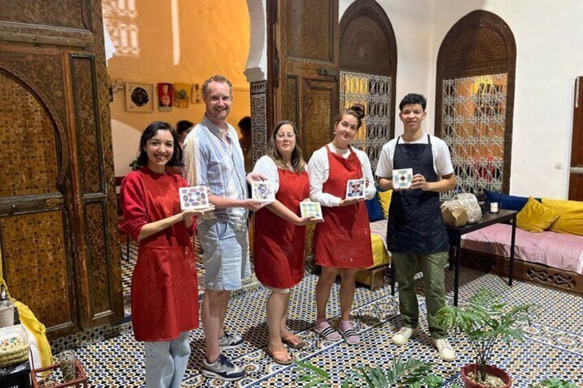 A group of people in a traditional setting with patterned floor tiles and wooden doors. 1