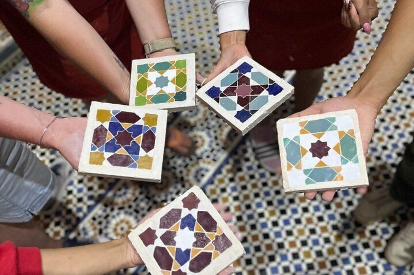 A group of people holding square tiles with mosaic patterns. 5
