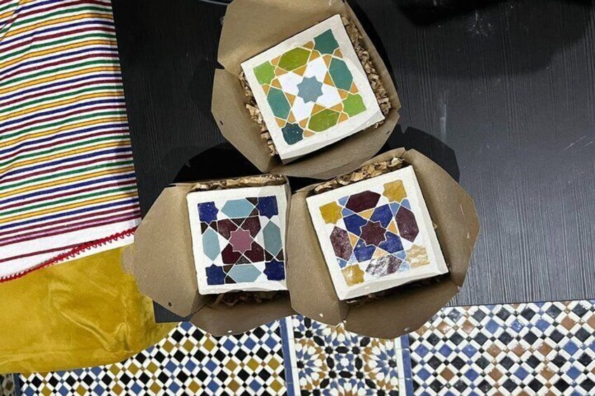 Three mosaic tiles in cardboard boxes, a striped pillow, and a patterned tablecloth. 3