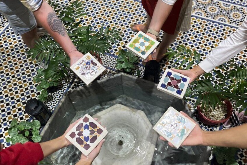 A group of people holding tiles around a water feature. 4